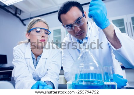 Science students using pipette to fill beaker at the university