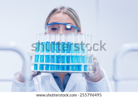 Science student holding tray of test tubes at the university