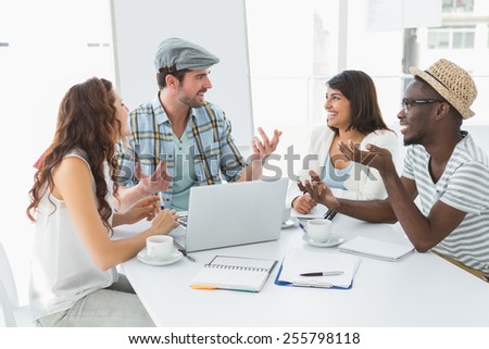Smiling colleagues interacting and using laptop in the office