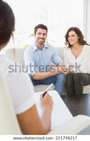 Reconciled couple smiling on couch in the therapist office
