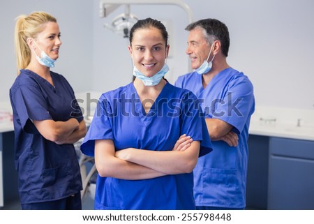 Smiling co-workers talking with arms crossed in dental clinic