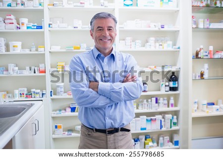 Portrait of a smiling pharmacist standing with arms crossed in the pharmacy
