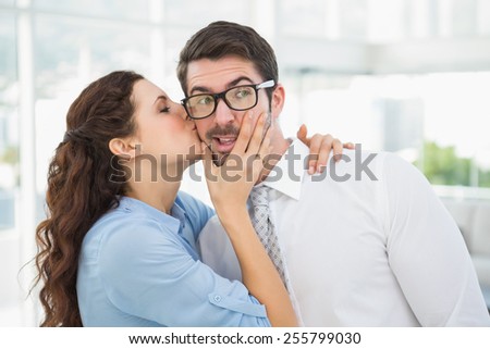 Businesswoman kissing her handsome colleague in the office