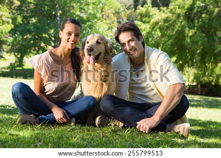 Happy couple with their pet dog in the park on a sunny day