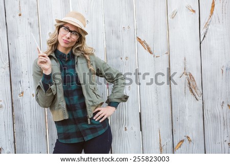 Pretty blonde posing in hat and holding against bleached wooden planks