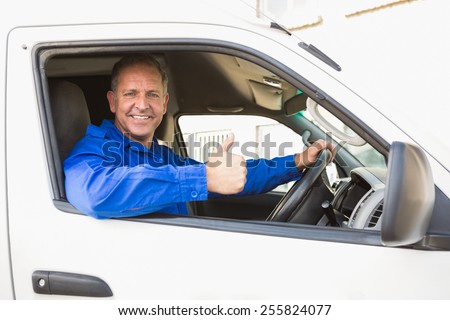 Delivery driver showing thumbs up driving his van outside the warehouse