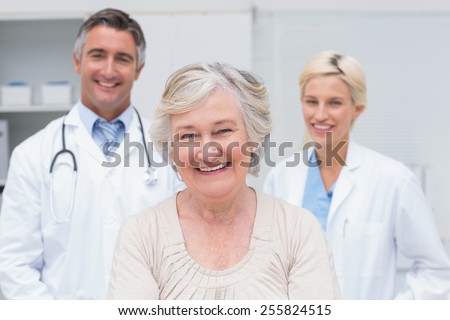 Portrait of senior patient smiling with doctors in clinic