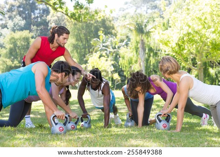 Fitness group planking in park with coach on a sunny day
