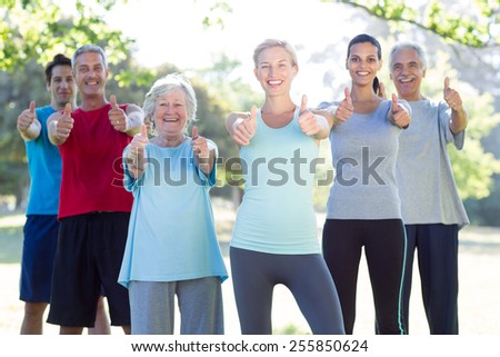 Happy athletic group smiling at camera with thumbs up on a sunny day