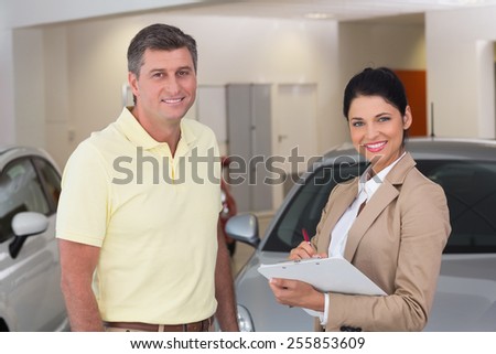 Smiling businessman undersign a car contract at new car showroom