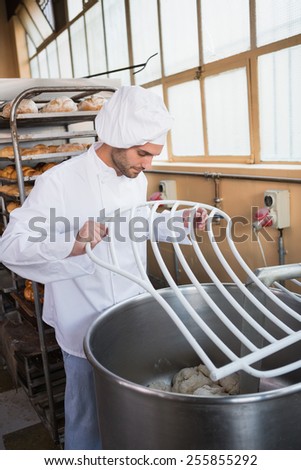 Baker preparing dough in industrial mixer at the bakery