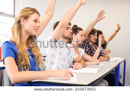Side view of students raising hands in classroom