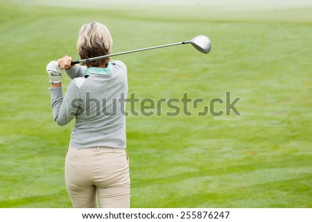 Lady golfer teeing off for the day on a foggy day at the golf course