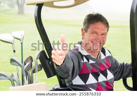 Happy golfer driving his golf buggy smiling at camera on a foggy day at the golf course
