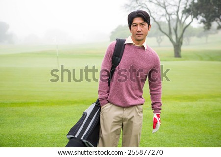 Golfer standing holding his golf bag at the golf course