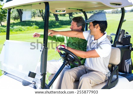 Golfing friends driving in their golf buggy at the golf course