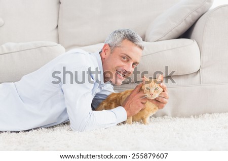 Portrait of happy man with dog lying on rug at home