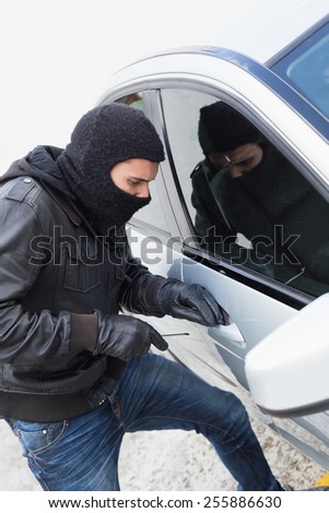 Thief breaking into a car in broad daylight