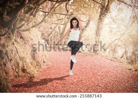 Fit woman doing aerobic exercise against peaceful autumn scene in forest