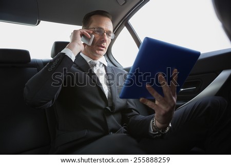 Businessman on the phone holding tablet pc in his car