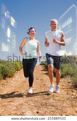 Fit couple running down mountain trail against fitness interface