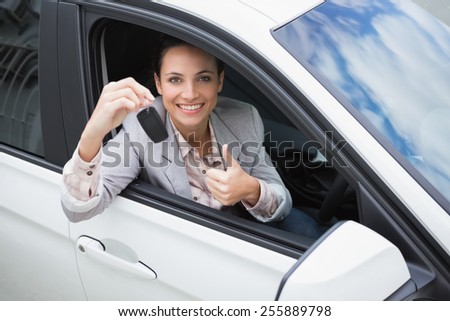 Pretty woman giving thumbs up while holding key in her car