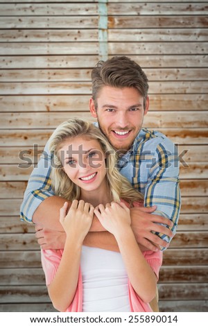 Attractive young couple smiling at camera against wooden background in pale wood