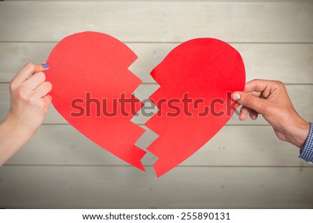 Two hands holding broken heart against bleached wooden planks background