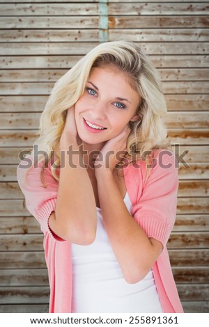 Pretty young blonde smiling at camera against wooden background in pale wood