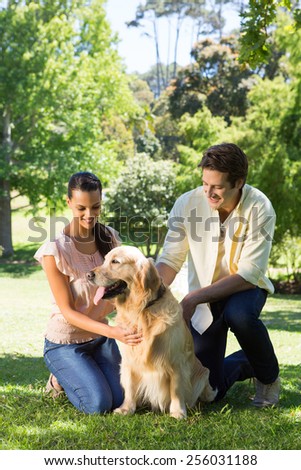Happy couple with their pet dog in the park on a sunny day