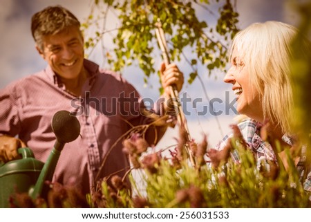 Happy mature couple gardening together outside in the garden