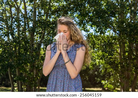 Pretty blonde blowing a her nose on a summers day