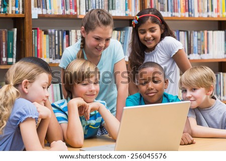 Cute pupils using tablet computer in library at the elementary school