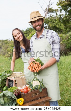 Couple selling organic vegetables at market on a sunny day