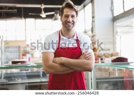 Portrait of happy server with arms crossed at the bakery