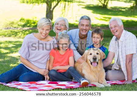 Happy family smiling at the camera with their dog on a sunny day