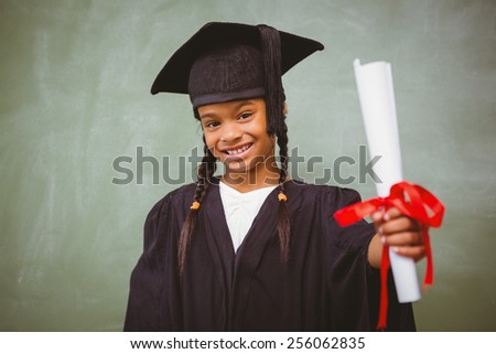Portrait of cute little girl in graduation robe holding diploma