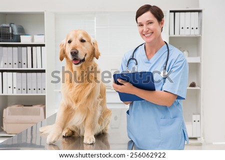 Vet examining a dog and writing on clipboard in medical office