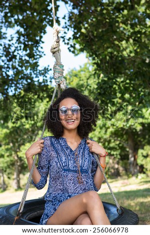Pretty young woman in tire swing on a summers day