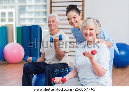 Portrait of happy female instructor with senior couple in gym