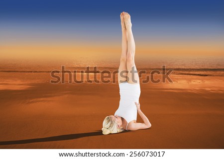 Fit young woman doing the shoulder stand pose against hazy blue sky