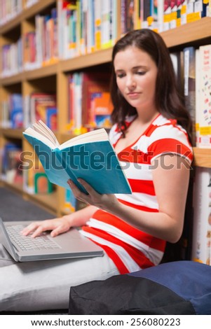 Student sitting on floor in library reading at the university
