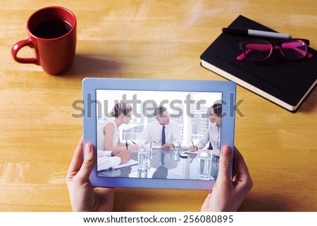 Businesswoman using tablet at desk against serious businessman during a meeting talking to his employees