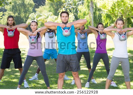 Fitness group working out in park with kettle bells on a sunny day