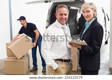 Managers smiling at camera with delivery driver behind in a large
