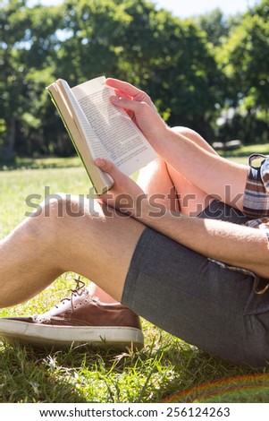 Handsome hipster reading book in park on a summers day