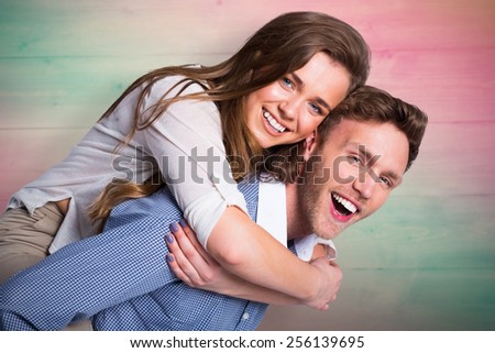 Smiling young man carrying woman against pink and green planks
