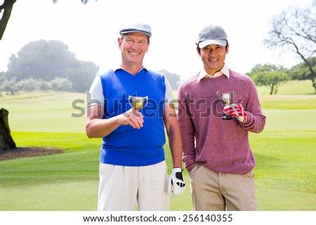 Golfing friends holding cups smiling at camera at golf course