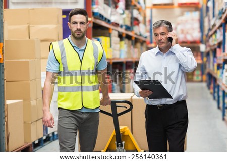 Worker walking with his manager over the phone in warehouse