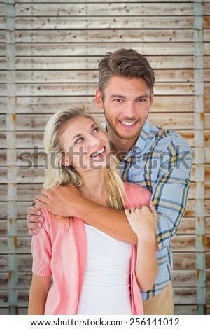 Attractive young couple smiling together against wooden background in pale wood